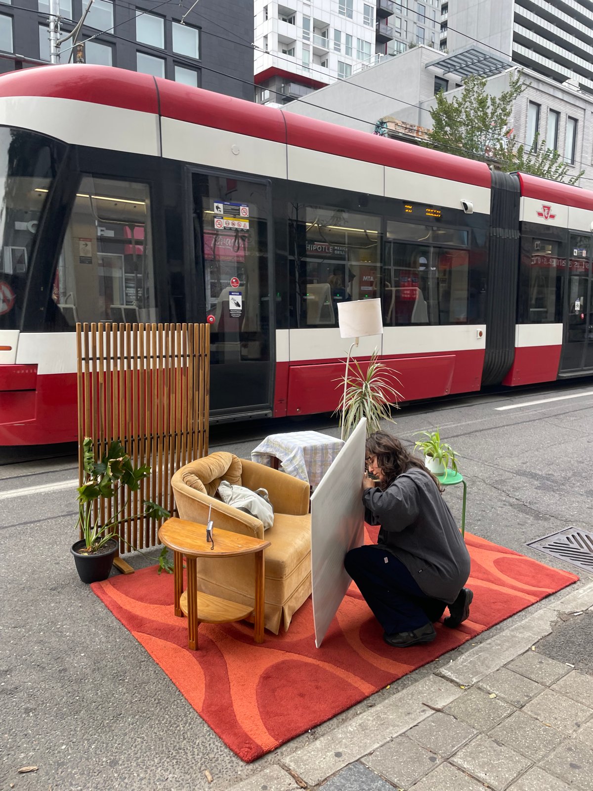 Strangers Calling living room set-up on the sidewalk with a streetcar passing